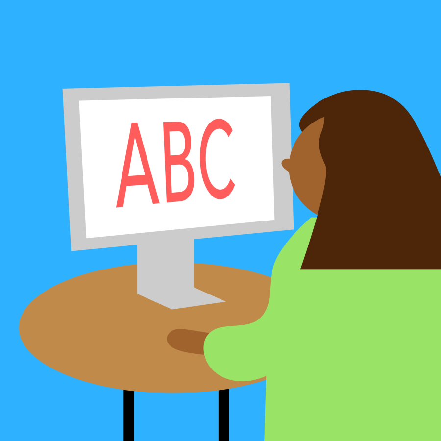 A woman sitting at a desk in front of a screen that shows the letters ABC.