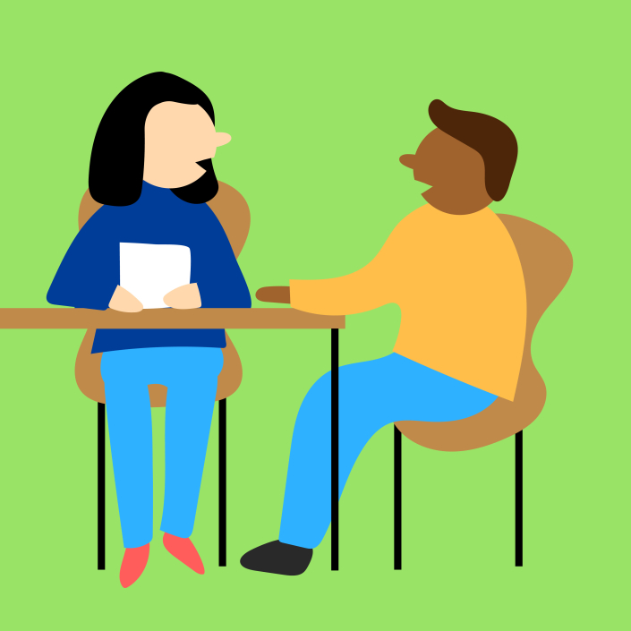 A man and a woman sitting at a table having a coaching conversation.